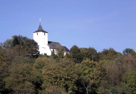 L'église St. Apollonia de Gransdorf trône sur une colline boisée sous un ciel bleu et clair., © Doris Pauels L'église St. Apollonia de Gransdorf trône sur une colline boisée sous un ciel bleu et clair., © Doris Pauels