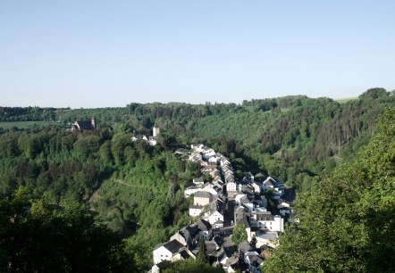 Panoramablick auf Kyllburg mit Kirche und Häusern, eingebettet in grüne Wälder und Hügel unter klarem Himmel., © TI Bitburger Land Panoramablick auf Kyllburg mit Kirche und Häusern, eingebettet in grüne Wälder und Hügel unter klarem Himmel., © TI Bitburger Land