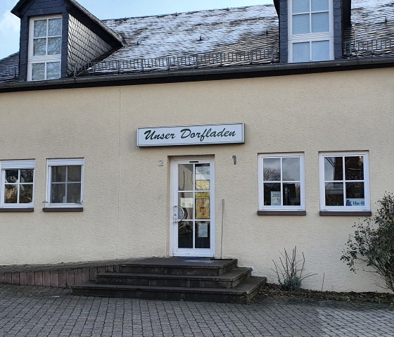 Gelbes Gebäude mit Schild 'Unser Dorfladen' über dem Eingang. Pflastersteine und ein kleiner Busch davor., © TI Bitburger Land - Steffi Wagner Gelbes Gebäude mit Schild 'Unser Dorfladen' über dem Eingang. Pflastersteine und ein kleiner Busch davor., © TI Bitburger Land - Steffi Wagner