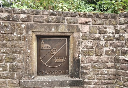 Mur de pierre avec un blason de Gransdorf représentant une église, deux anneaux et une couronne. A droite, on peut voir un tuyau d'évacuation., © TI Bitburger Land S.Wagner Mur de pierre avec un blason de Gransdorf représentant une église, deux anneaux et une couronne. A droite, on peut voir un tuyau d'évacuation., © TI Bitburger Land S.Wagner