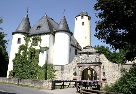 Rittersdorf Castle with two round towers and a high yellow tower. An archway with decorations leads into the castle. Ivy grows on the walls., © Frank Schaal Rittersdorf Castle with two round towers and a high yellow tower. An archway with decorations leads into the castle. Ivy grows on the walls., © Frank Schaal