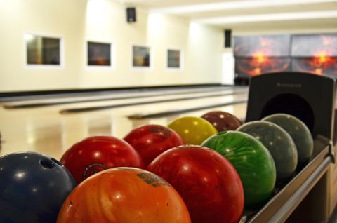 Eine Bowlingbahn mit bunten Bowlingkugeln in einer Anlage. Die Umgebung ist hell und einladend.