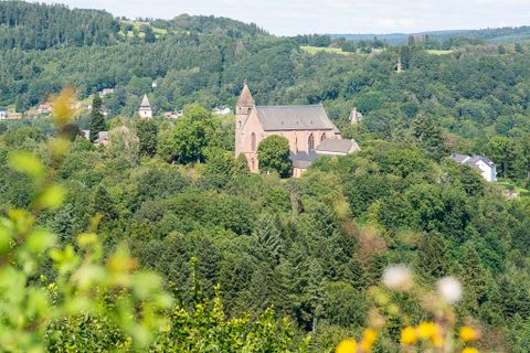 Blick auf eine Kirche inmitten von grünen Wäldern und Hügeln.