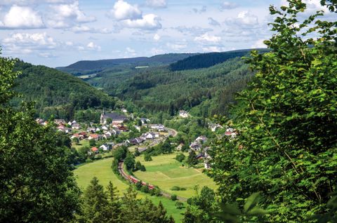 Landschaftsansicht von St. Thomas mit grünen Hügeln und einem Dorf im Tal.