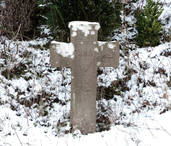 Ein Steinkreuz steht im Schnee, umgeben von winterlicher Vegetation am Mühlenweg Speicher., © Eifelverein Ortsgruppe Speicher