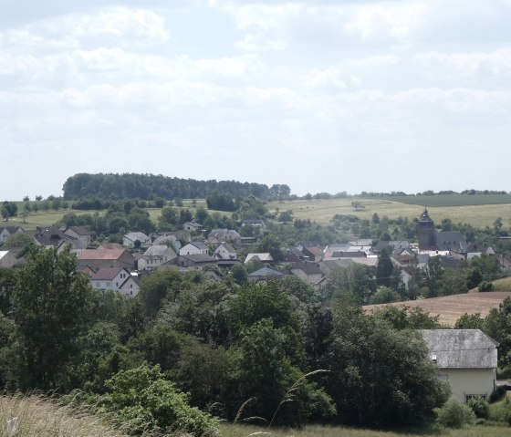 Panoramablick auf Gransdorf, umgeben von grünen Feldern und Hügeln. Im Dorf sind Häuser und ein Kirchturm zu sehen., © TI Bitburger Land