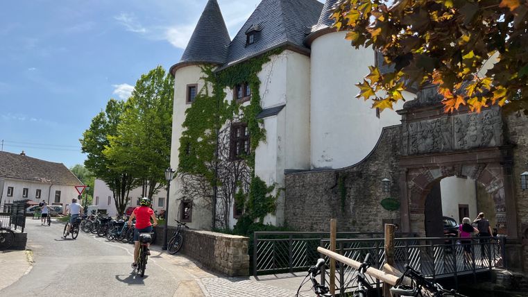 Man sieht einen Turm der Burg Rittersdorf und Radfahrer. Es ist eine Station auf dem Raderlebnistag Nimms Rad