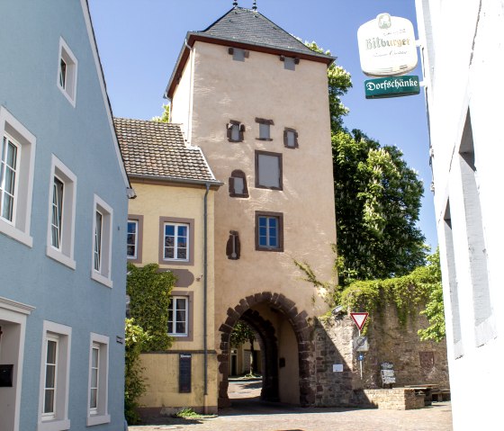 The Upper Gate in Dudeldorf, a historic town gate, surrounded by colorful houses and a street sign. Sunny day with a blue sky., &copy; Tourist-Information Bitburger Land_M. Mayer