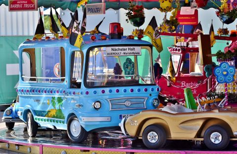 A colorful children's carousel with a blue ride and a golden car. The rides are decorated and invite children to play.