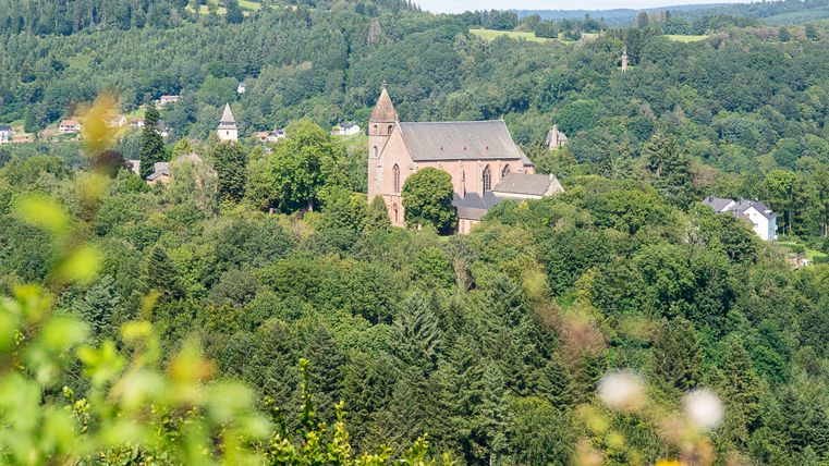 Blick auf eine Kirche inmitten von grünen Wäldern und Hügeln.