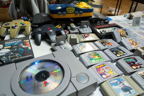 A table with various video game consoles, controllers, and game cartridges. Underneath are well-known games and hardware from brands like PlayStation and Nintendo.