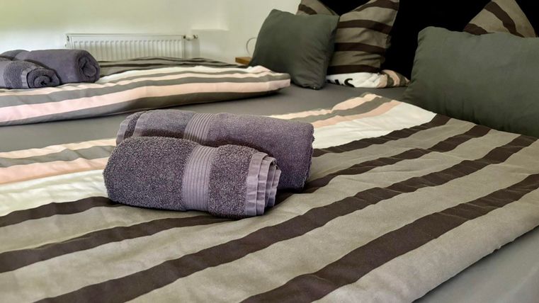 Une chambre confortable avec un lit double. Les draps sont rayés et de serviettes fraîches sont soigneusement placées sur le lit.