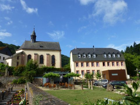 Ein malerisches Dorf mit einer historischen Kirche und einem modernen Gebäude. Die Umgebung ist grün und einladend.