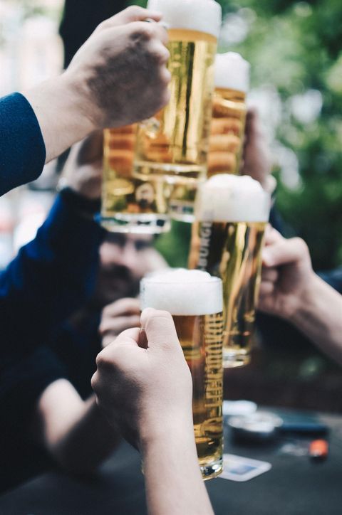 A group toast with beer glasses in a convivial gathering. The glasses are filled with golden beer and have a rich head.