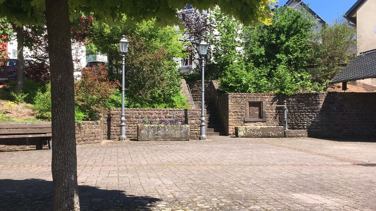 Dorfplatz in Gransdorf mit Baum, Stein und Laternen.