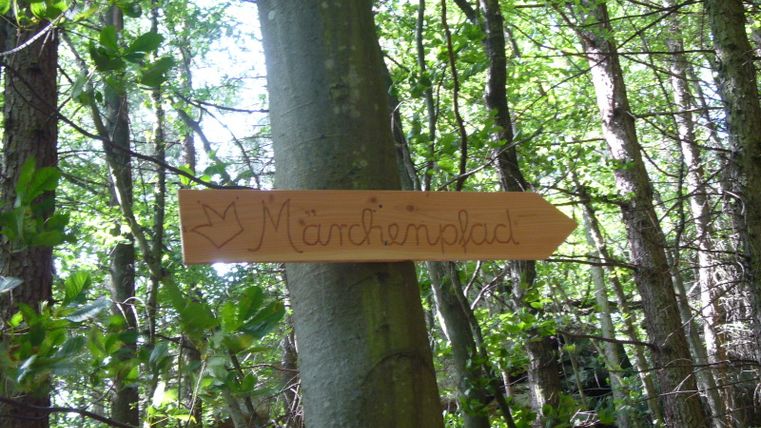Holzschild mit der Aufschrift 'Märchenpfad' im Wald.