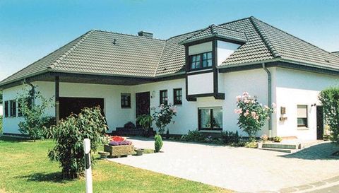 Ein modernes Einfamilienhaus mit einem Garten. Es hat ein helles Äußeres und einen gepflasterten Weg.