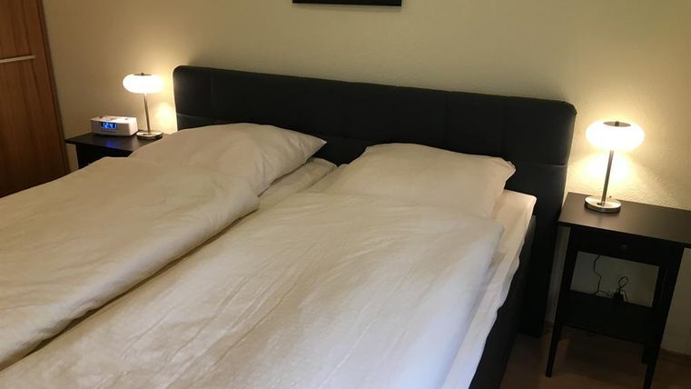 Ein modernes Schlafzimmer mit einem Doppelbett und zwei Nachttischen. Die Beleuchtung ist sanft und schafft eine gemütliche Atmosphäre.