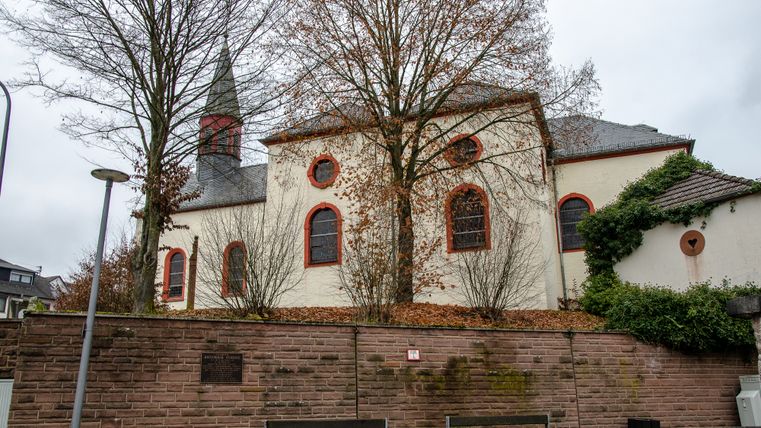 Kerk in Wißmannsdorf met bomen en stenen muur op de voorgrond.