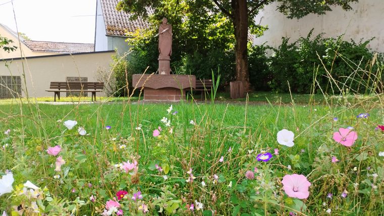 Statue von Donatus in einem Garten mit Blumen im Vordergrund.