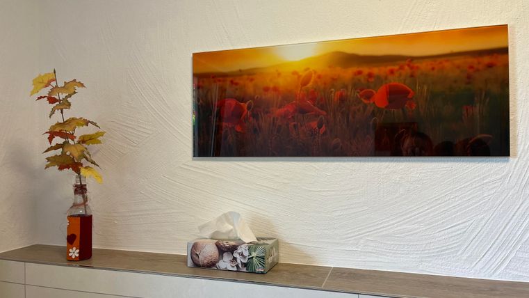 Een moderne kamer met een lange wandkunst boven een dressoir. De wandkunst toont flamingo's voor een zonnig, oranje landschap.