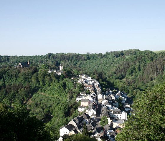 Panoramablick auf Kyllburg, umgeben von dichten Wäldern und Hügeln, mit einer Kirche und Häusern im Tal., © TI Bitburger Land
