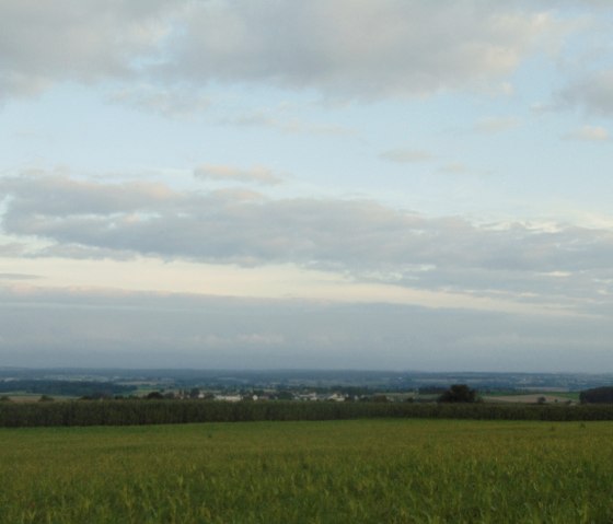 Weite Landschaft mit gr&uuml;nen Feldern und einem bew&ouml;lkten Himmel. Im Hintergrund sind H&uuml;gel und W&auml;lder zu sehen., &copy; Conny Meier