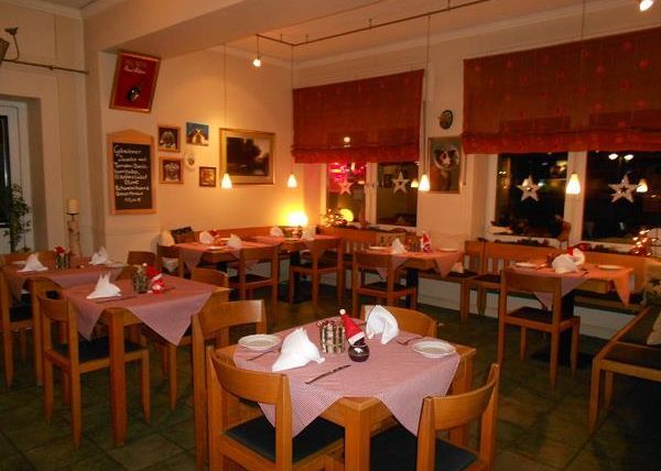 Ein gemütliches Restaurant mit Holztischen und Stühlen. Die Tische sind liebevoll gedeckt und die Beleuchtung sorgt für eine einladende Atmosphäre.