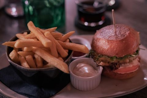 Ein leckerer Burger mit frischem Salat und einer Portion Pommes frites. Dazu gibt es Ketchup und Mayo in kleinen Schälchen.