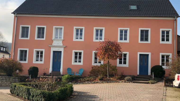 Altes Bauernhaus mit rosa Fassade und blauen Türen in Oberweis.