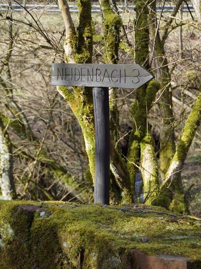 Wegwijzer met het opschrift 'Neidenbach 3' in een bos.