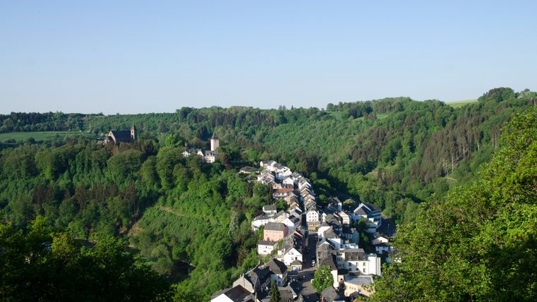 Blick auf Kyllburg von einer erhöhten Plattform, umgeben von grünen Wäldern und Hügeln.