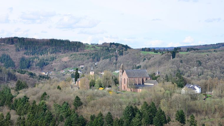 Landschap met kerk en heuvels op de achtergrond.