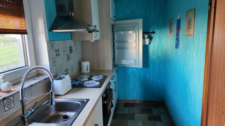 Eine helle Küche mit blauen Wänden und modernen Möbeln. Die Küche ist gut ausgestattet mit einem Spülbecken, Herd und Kühlgerät.