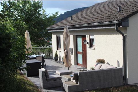Een modern terras met comfortabele meubels en parasols. Op de achtergrond staat een helder huis omringd door bomen.