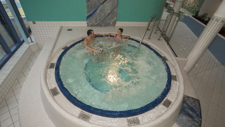 Ein Whirlpool in einem modernen Spa-Bereich. Zwei Personen entspannen im Wasser.