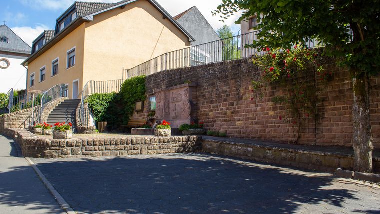 Un parking vide à côté d'une église avec un bâtiment jaune et un mur en pierre.