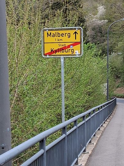 Ein Wegweiser zeigt die Richtung nach Malberg, 1 km entfernt. Die Stadt Kyllburg ist durchgestrichen.