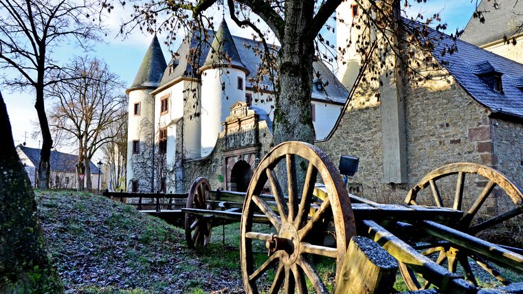 Burg Rittersdorf im Winter mit alten Holzwagenrädern im Vordergrund.