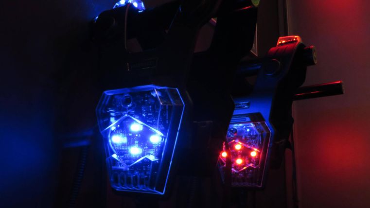 Zwei leuchtende Geräte mit blauen und roten LED-Lichtern. Sie sind an einer Wand angebracht und erzeugen eine futuristische Atmosphäre.