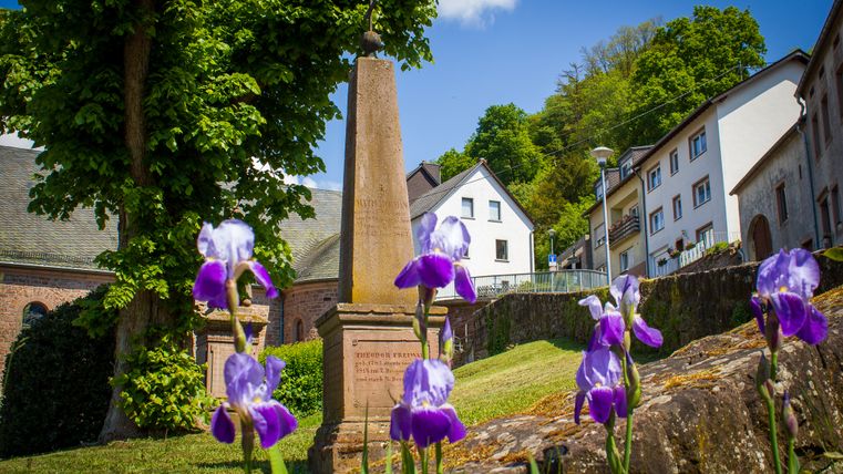Blumen vor einem Obelisken und Gebäuden in Kyllburg.