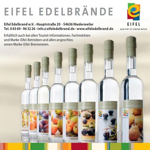 Ein Sortiment von Eifeler Edelbränden in klaren Flaschen. Die Flaschen zeigen verschiedene Obstsorten, die für die Herstellung verwendet werden.