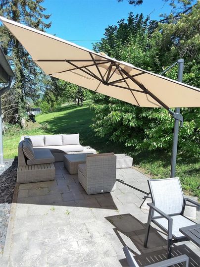Une terrasse confortable avec des meubles modernes et un grand parasol. L'environnement verdoyant crée une atmosphère relaxante.