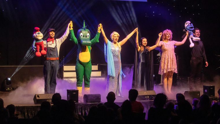 Une spectacle en direct avec différents personnages et interprètes sur scène. Les artistes reçoivent un applaudissement final ensemble.