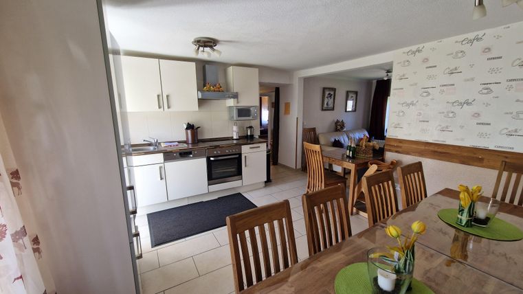 Eine moderne Küche mit hellen Möbeln und einem Esstisch. Die Dekoration ist freundlich und einladend.