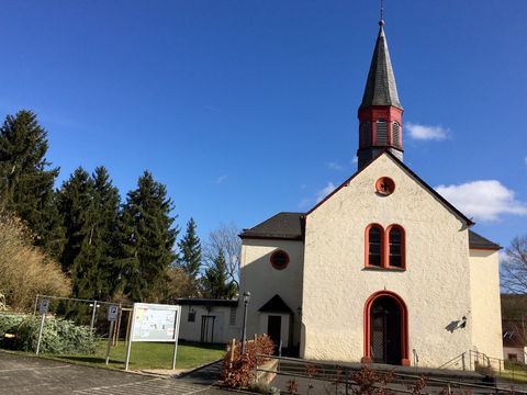 Église de Wißmannsdorf avec une tour pointue et un ciel bleu.