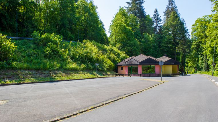 Parking vide avec un petit bâtiment et des arbres en arrière-plan.