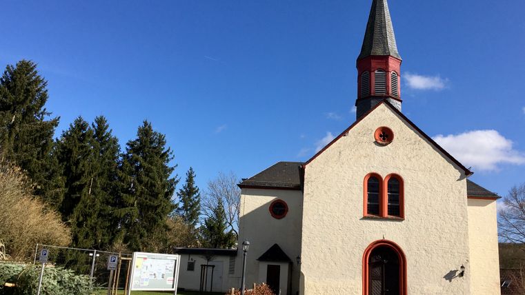 Église de Wißmannsdorf avec une tour pointue et un ciel bleu.
