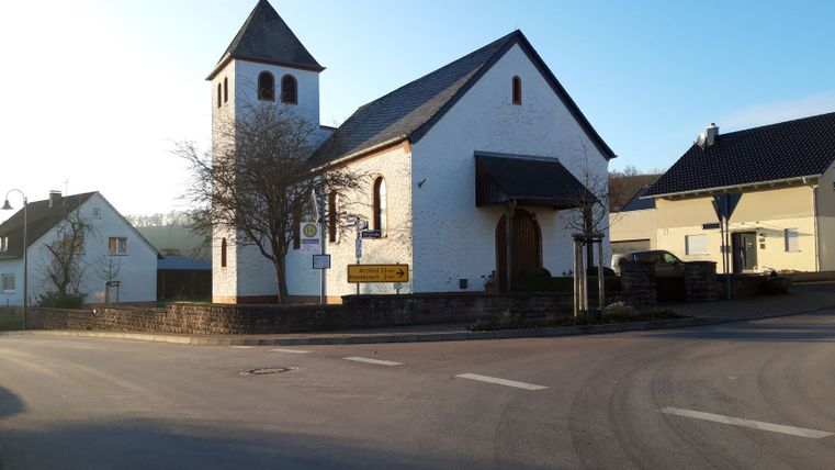 Kerk in Wißmannsdorf bij zonsondergang met omliggende huizen.