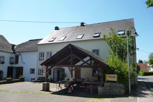 Ein gemütliches Gebäude mit einem großen Vordach in einer ruhigen Straße. Die Umgebung ist grün und einladend.